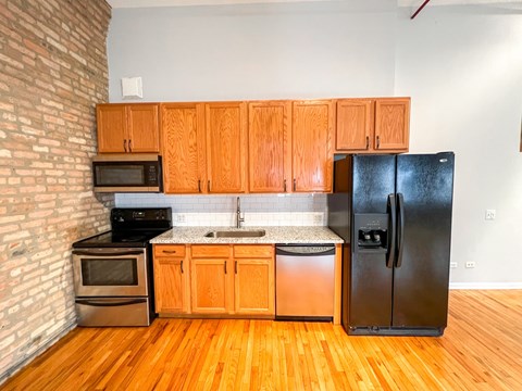 A kitchen with wooden cabinets and a black fridge.