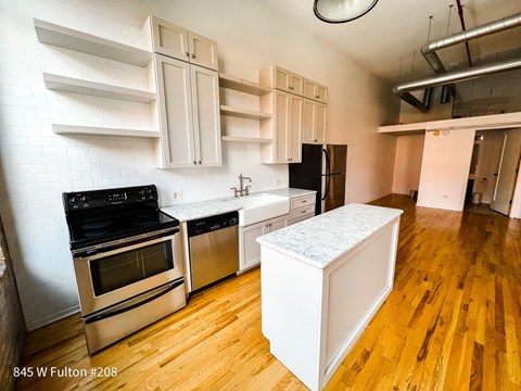 A kitchen with a white island and stainless steel appliances.