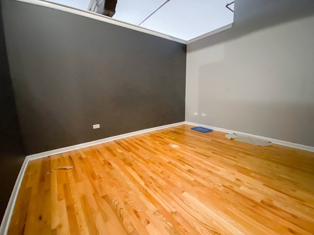 a room with a wooden floor and a gray wall and a window