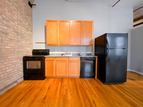 a kitchen with a black refrigerator and wooden cabinets