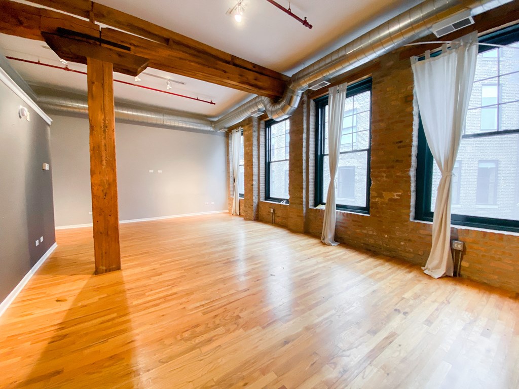 an empty room with wood floors and windows