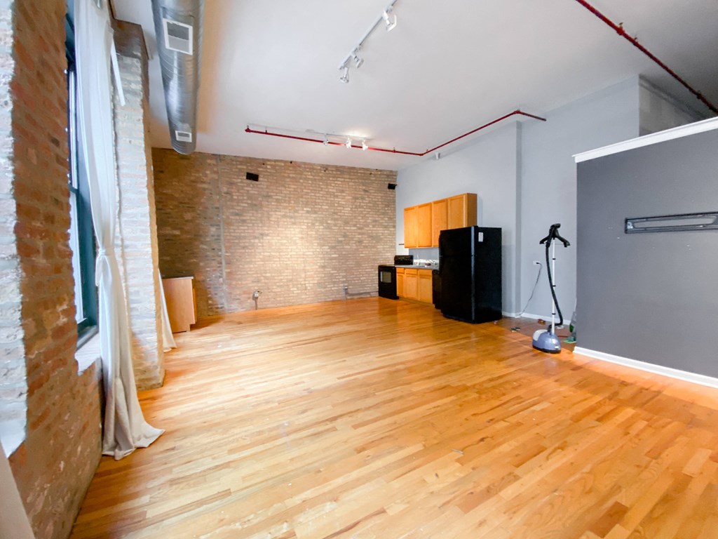 an empty living room with wood floors and a brick wall