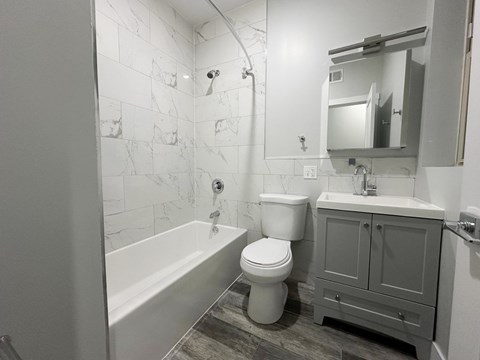 A white toilet sits next to a bathtub in a bathroom.
