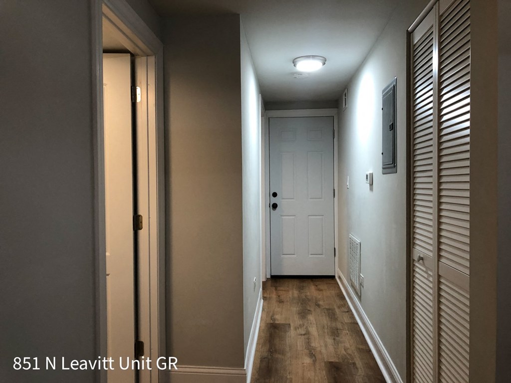 a hallway with a white door and a hallway light and a door to a closet