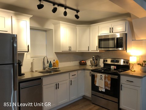 A kitchen with a black stove top oven and a black microwave above the stove.