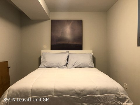 A bedroom with a bed, two pillows, and a painting on the wall.