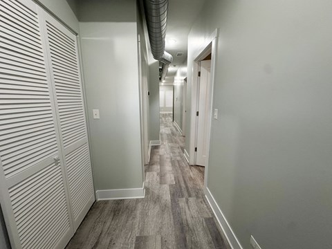 A long hallway with a carpeted floor and white walls.