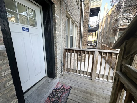 A balcony with a white door and a rug on the floor.