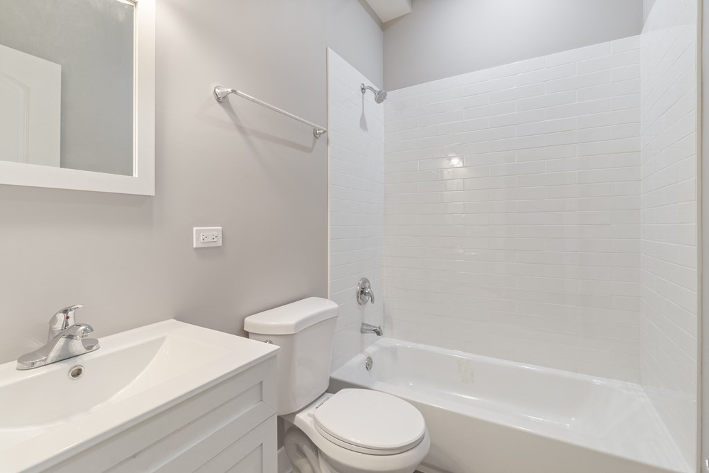 a white bathroom with a white toilet and tub and a sink