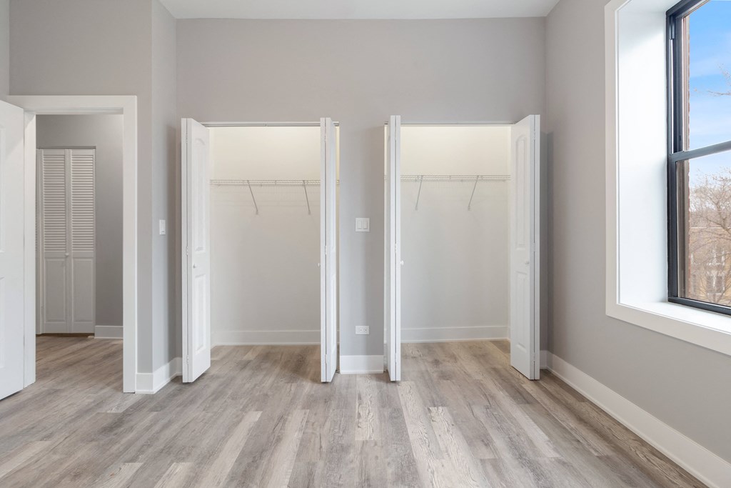 an empty room with three closet doors and a wood floor