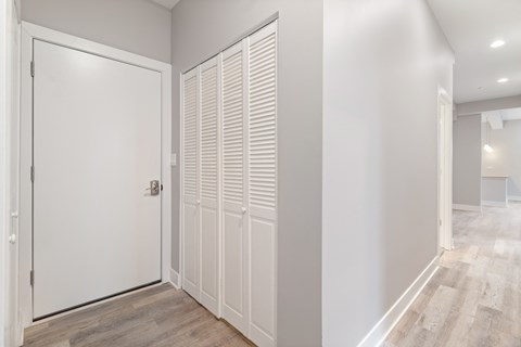 a long white hallway with a door to a closet