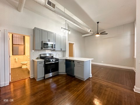 A kitchen with a wood floor and white walls.