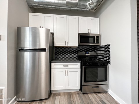 A kitchen with a stainless steel refrigerator, microwave, and oven.