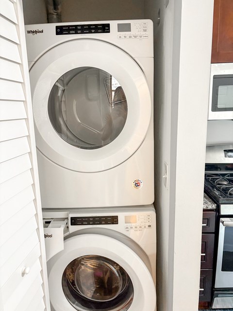 A white Whirlpool washing machine is in a cabinet.