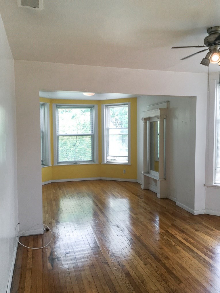 an empty living room with wood floors and a ceiling fan