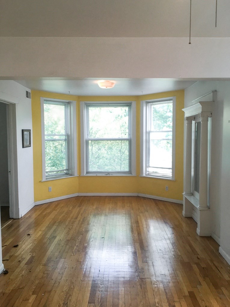 an empty living room with wood floors and large windows