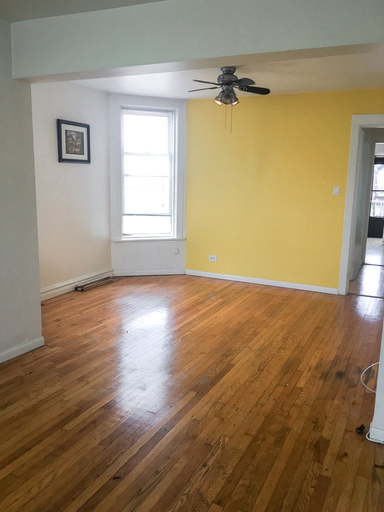 an empty living room with a yellow wall and wooden floors