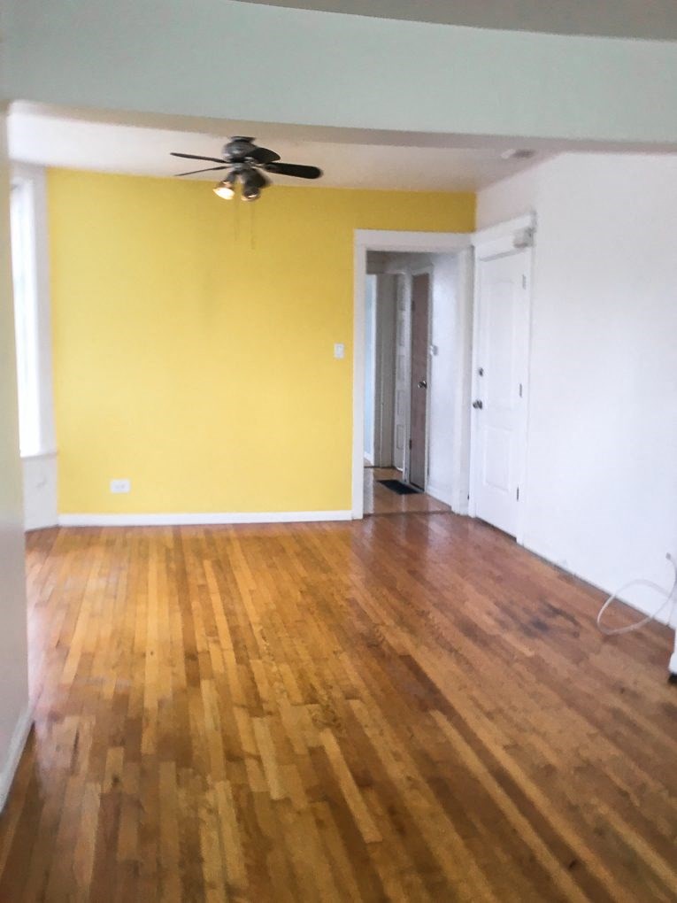 a living room with a yellow wall and a wooden floor