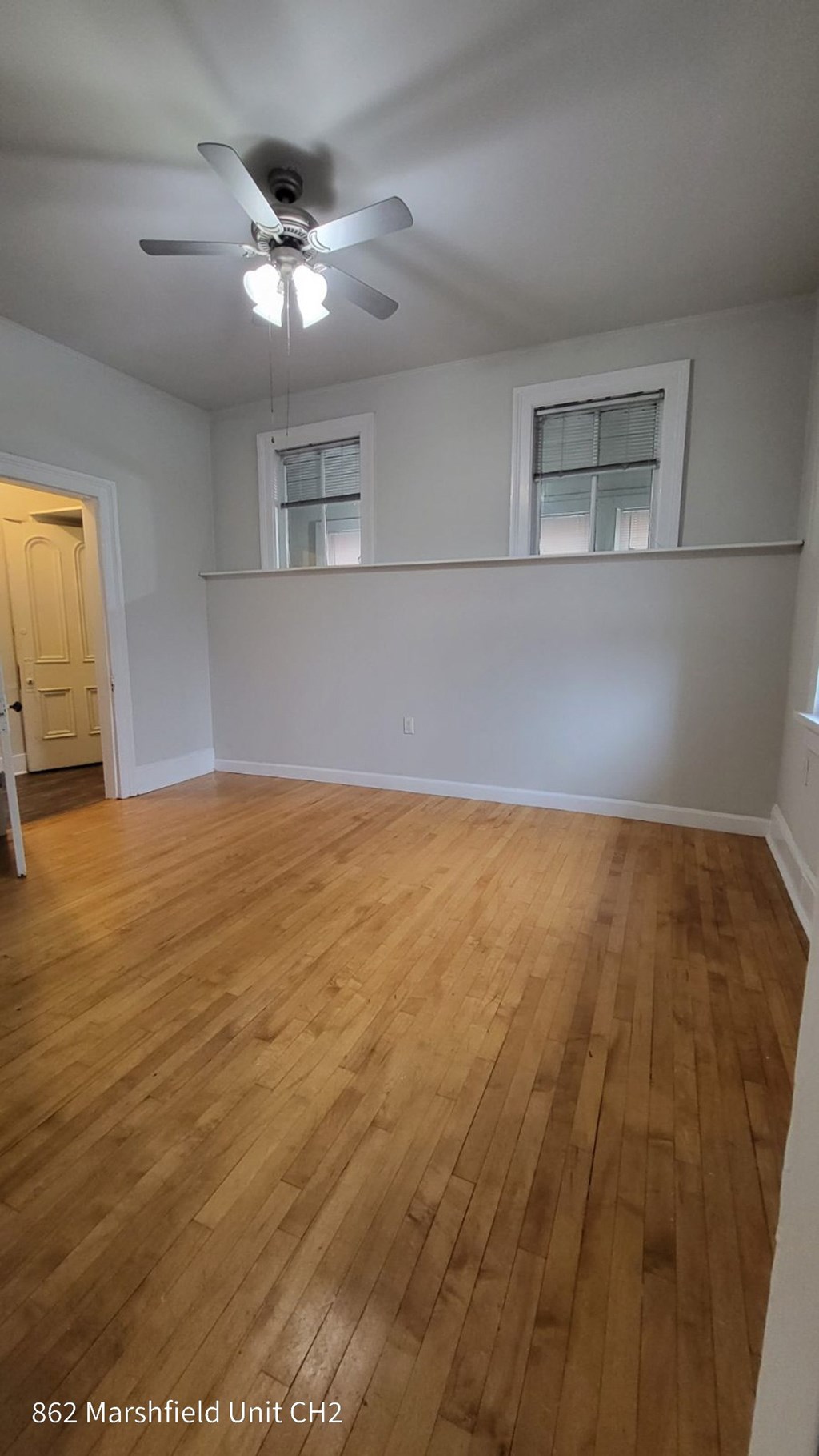 A room with a ceiling fan and wooden flooring.