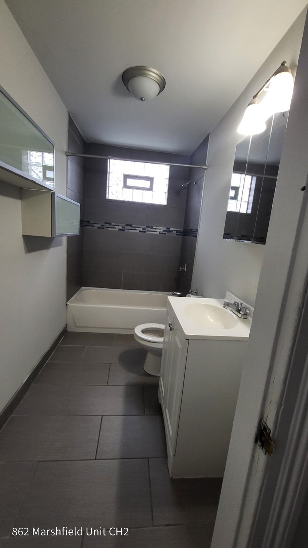 A bathroom with a toilet, sink, and mirror.