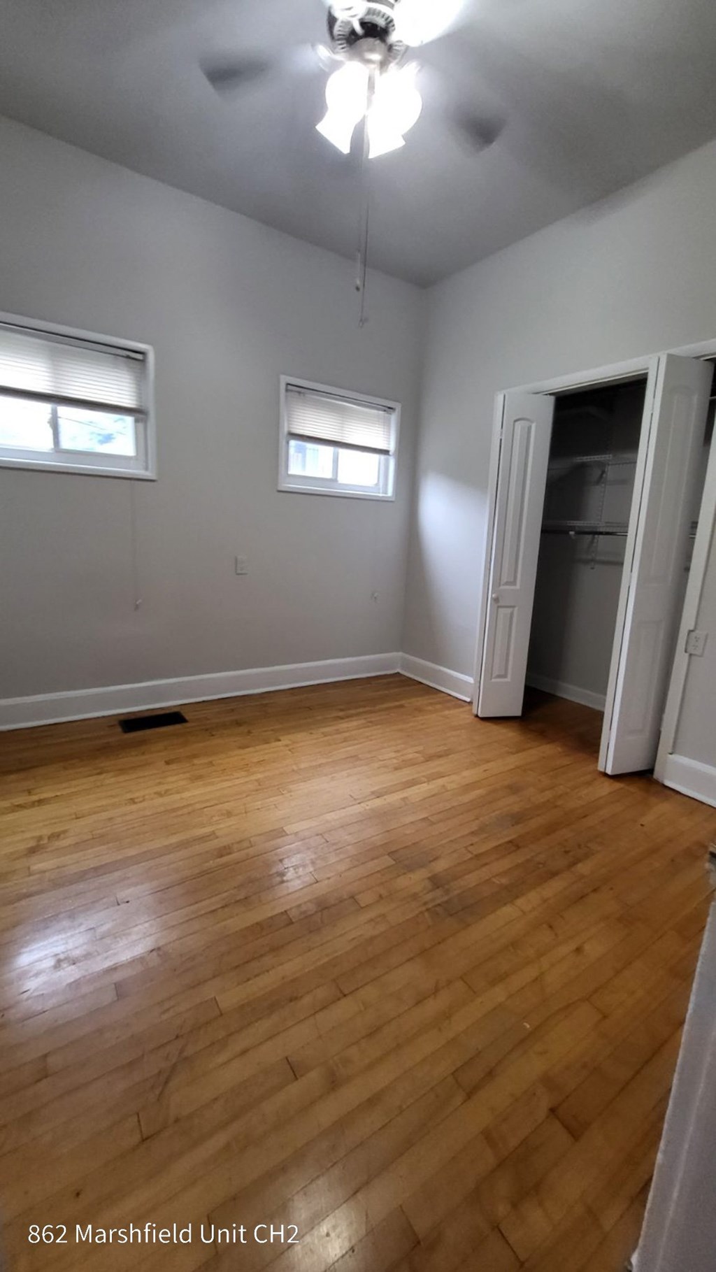 A room with wood flooring and two windows.
