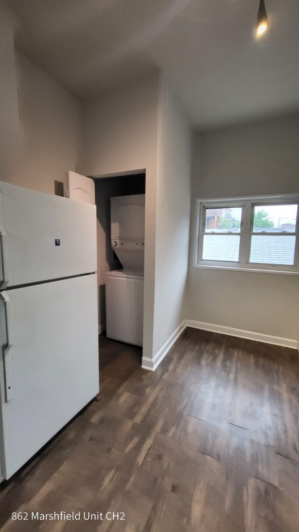 A kitchen with a white fridge and wooden floors.