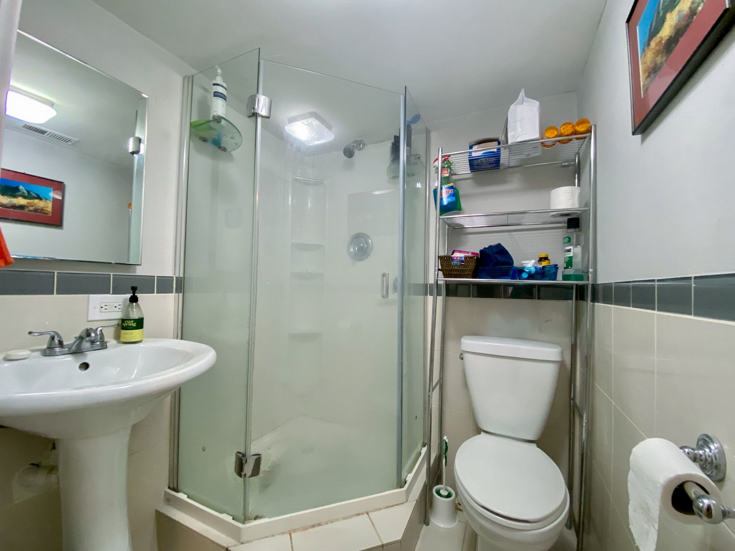 A white toilet is in a small bathroom with a sink and a shower.