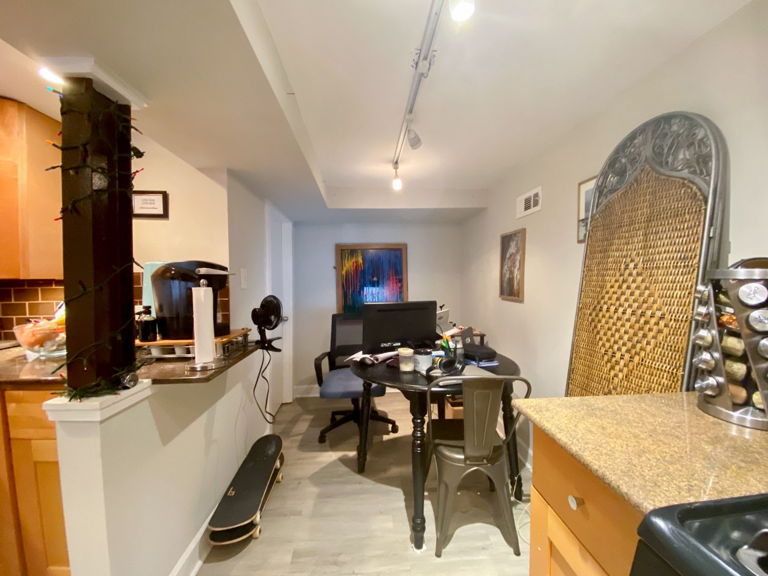 A room with a desk, chairs, and a skateboard.
