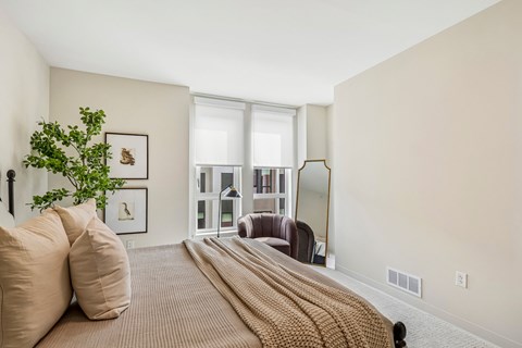 A bedroom with a large bed and a potted plant.