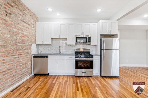 A kitchen with white cabinets and a brick wall.