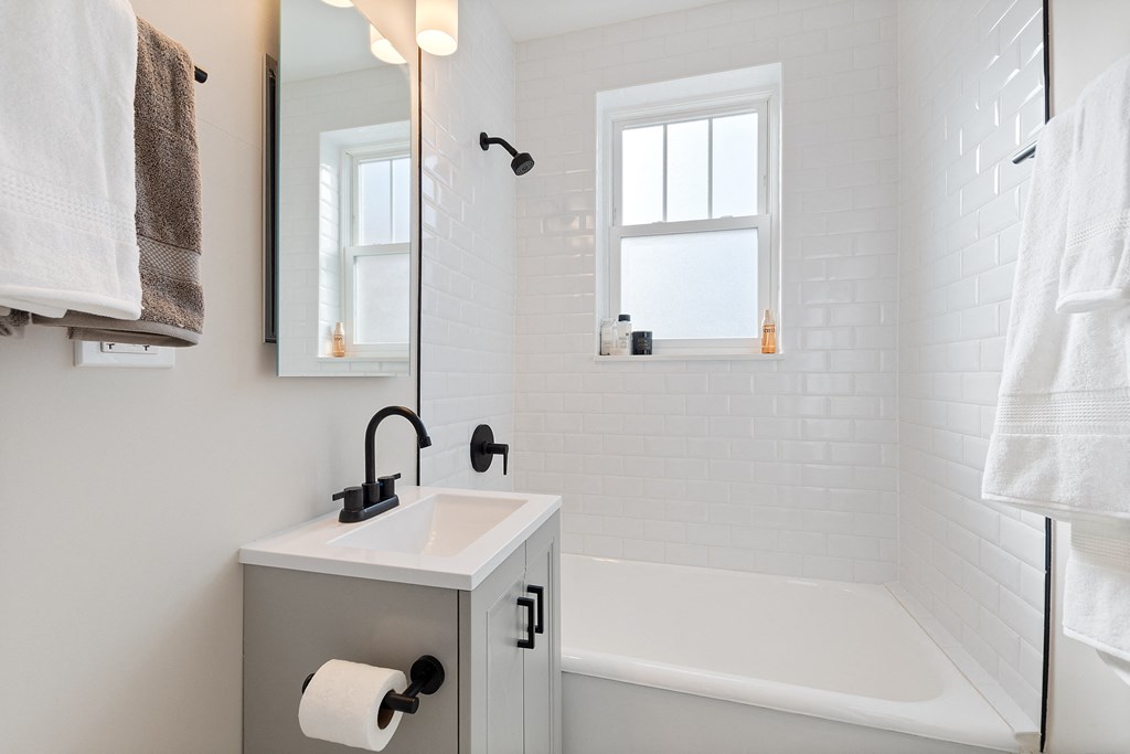 a white bathroom with a sink and a bath tub