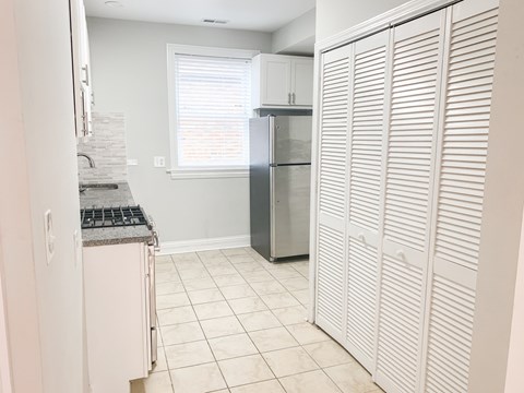 A kitchen with a refrigerator and a stove top oven.