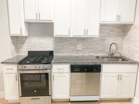 A kitchen with white cabinets and a black stove top oven.