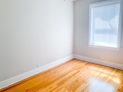 A room with a window and wooden flooring.