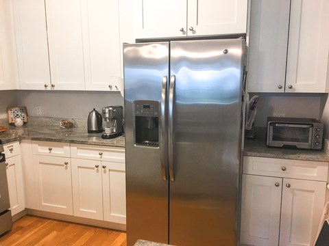 A kitchen with a stainless steel refrigerator and white cabinets.