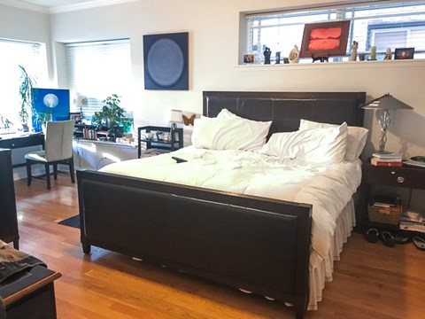 A bedroom with a large bed and a desk with a chair.