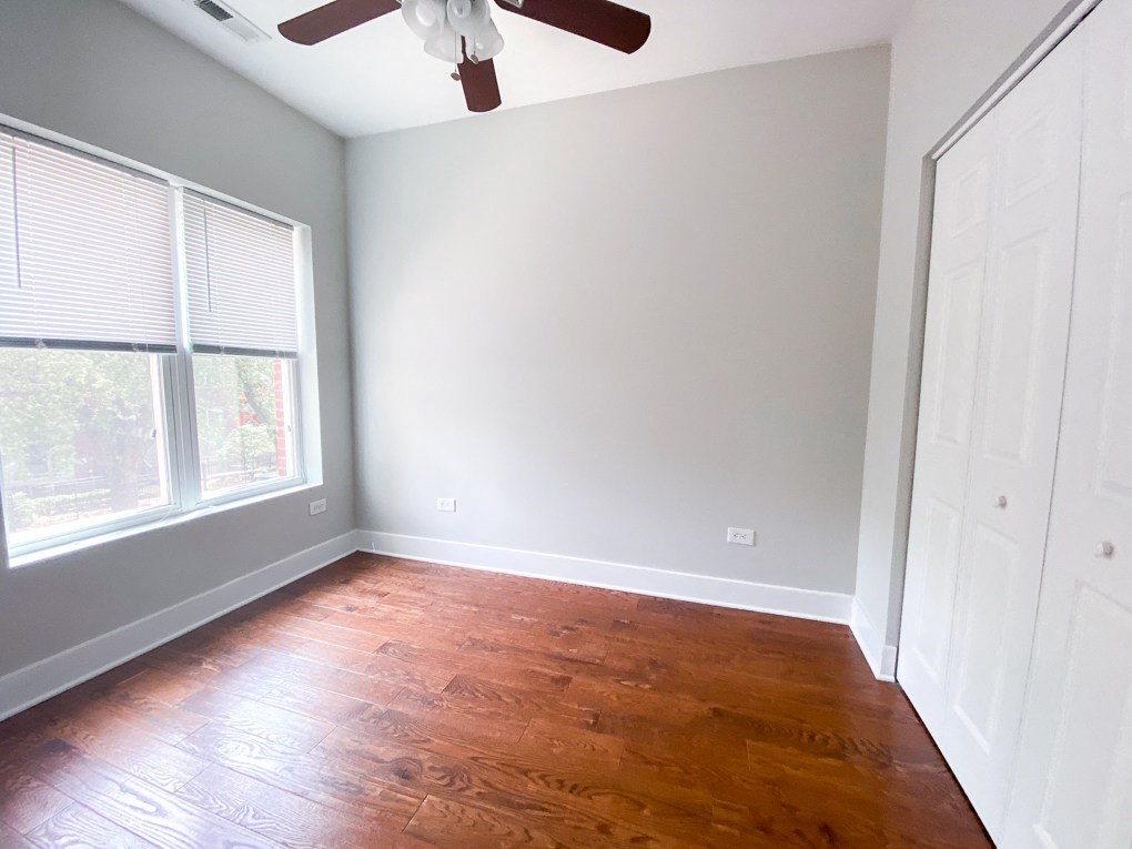 an empty bedroom with wood floors and a ceiling fan