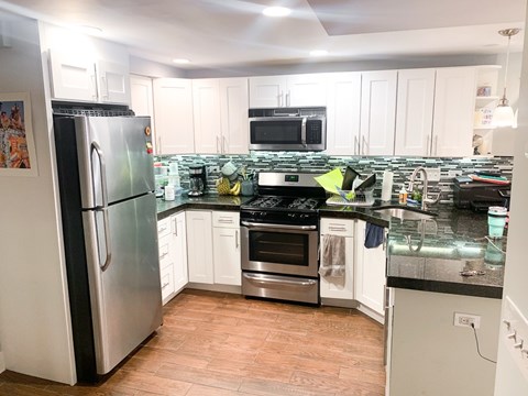 A kitchen with a refrigerator, oven, and microwave.