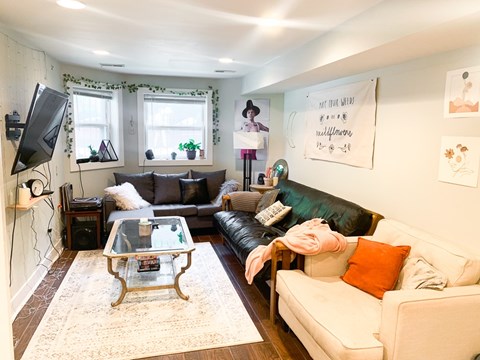 A living room with a white couch, a glass coffee table, and a television.
