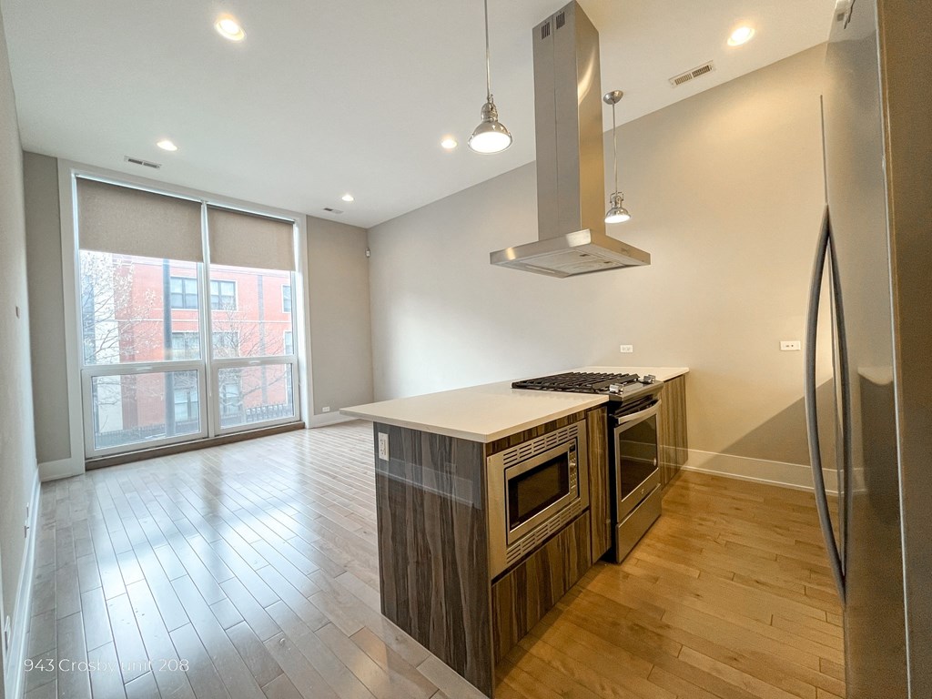 a kitchen and living room with a large window and wood flooring