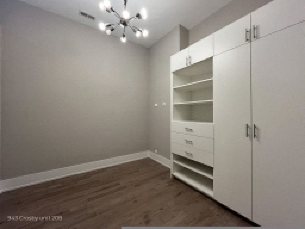 a bedroom with a closet with white cabinets and drawers