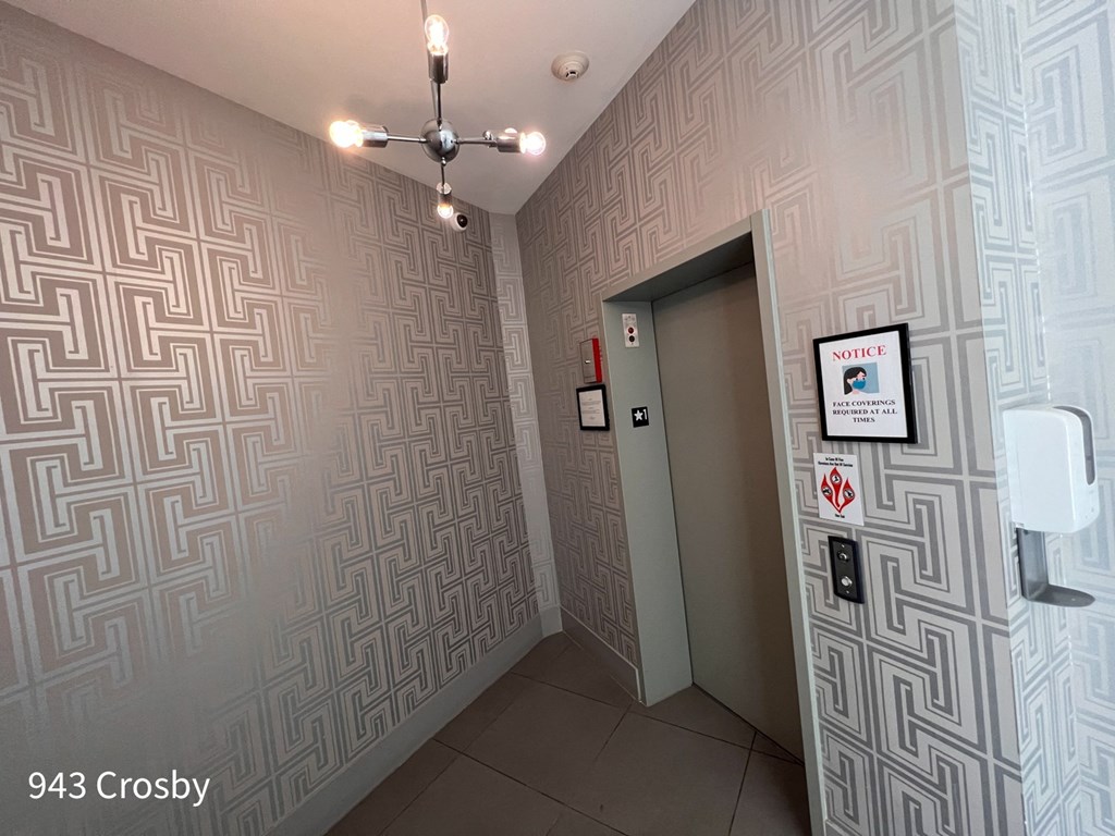 a gray wall with a geometric pattern in front of a gray door with a white ceiling fan