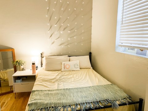 A bedroom with a bed, nightstand, and a wall decoration.