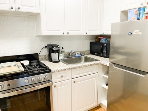 A kitchen with white cabinets and a stainless steel refrigerator.