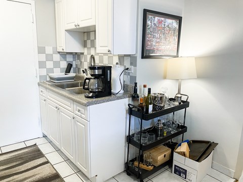 A kitchen with white cabinets and a black and white checkered backsplash.