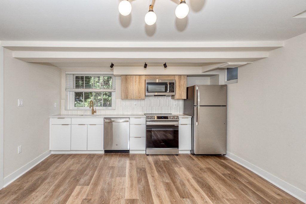 an empty kitchen with white cabinets and stainless steel appliances
