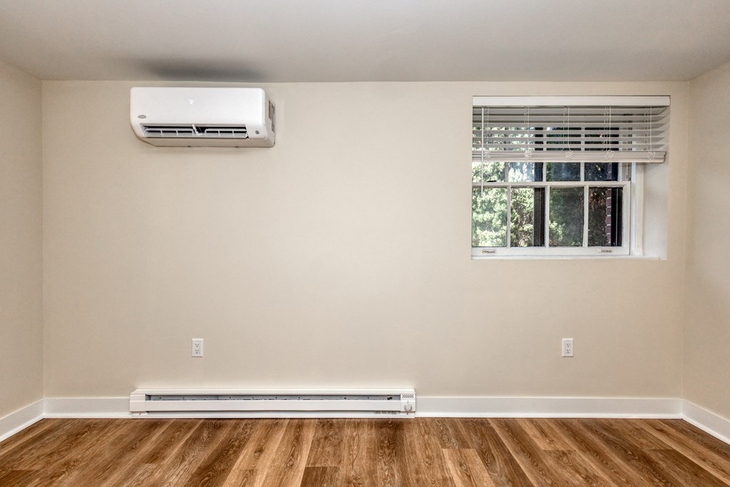 an empty room with a window and a air conditioner on the wall
