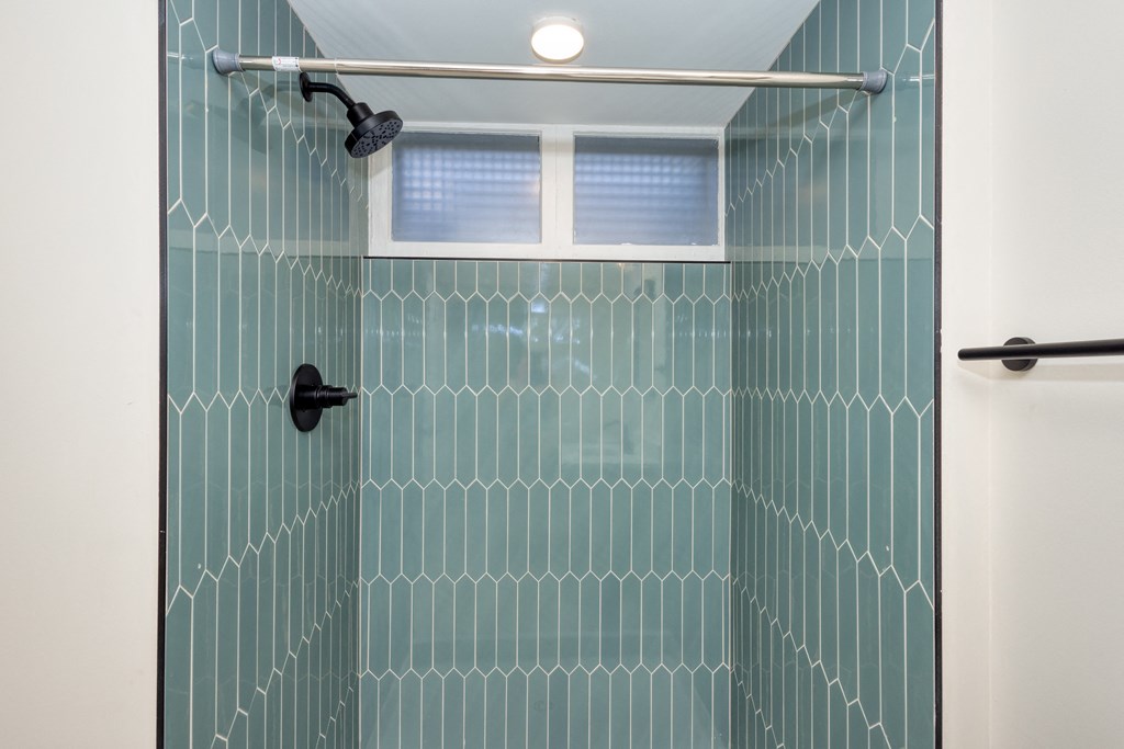 a bathroom with a shower with a blue tile wall and a shower curtain
