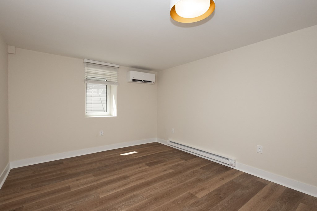 an empty room with hardwood flooring and a window