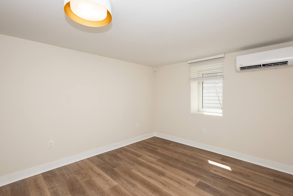 a living room with white walls and wood flooring and a window